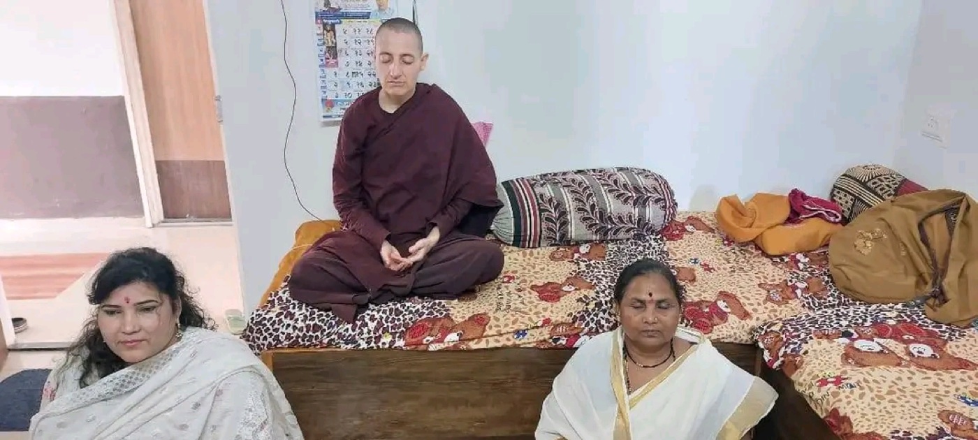 Bhadda Nyani seated in maroon robes in a room, with another person visible in the foreground.
